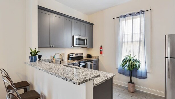 A kitchen with granite countertops, stainless steel appliances, and dark gray cabinets.
