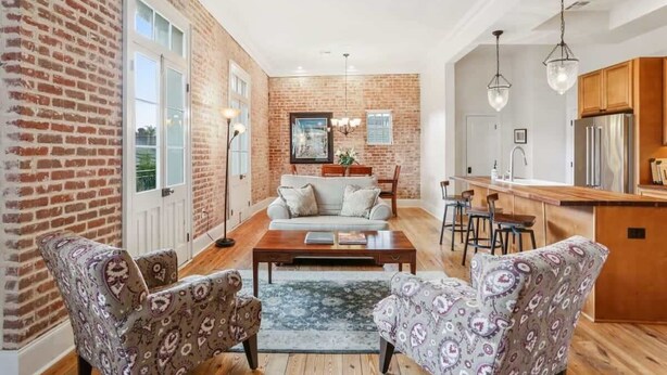 A spacious living room with a sofa, patterned chairs, a coffee table, and a dining area with chairs and a table.