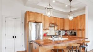 A modern kitchen with wooden cabinets, stainless steel appliances, and a central island with bar stools.