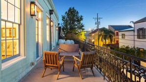 A balcony with wooden furniture, a railing, and a view of the street.