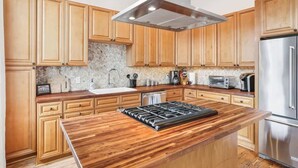 A modern kitchen with wooden cabinets, a stainless steel range, and a granite countertop.