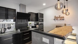 A modern kitchen with black cabinets, a central island, and pendant lighting.