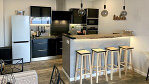 A modern kitchen with a central island, bar stools, and pendant lighting.