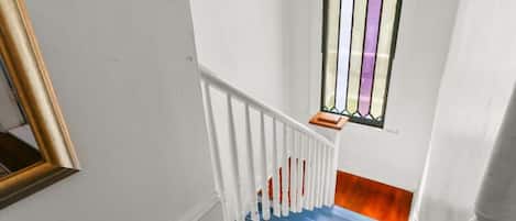 A staircase with white railings, a blue handrail, and a wooden floor.