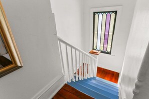 Een trap met witte leuningen, een blauwe handrail en een houten vloer.