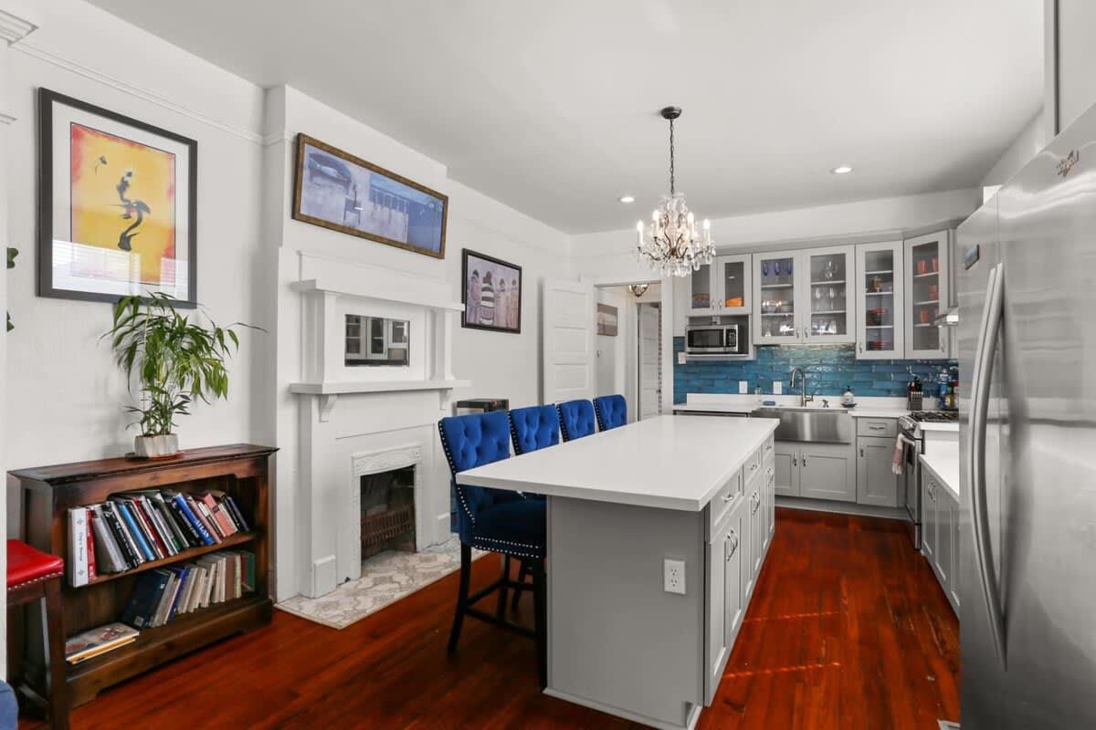 A modern kitchen with a central island, white cabinetry, and a built-in microwave.