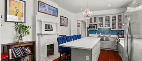 A modern kitchen with a central island, white cabinetry, and a built-in microwave.