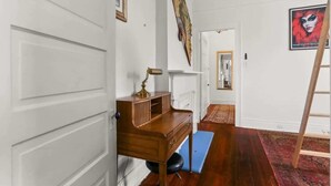 Un couloir avec un bureau en bois, un tapis rouge et une échelle appuyée contre le mur.