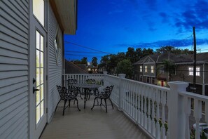 Une véranda avec une table et des chaises, des balustrades blanches et des maisons en arrière-plan.