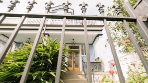 Une maison à deux étages avec une porte en bois portant le numéro « 4117 » et un balcon agrémenté de rampes de fer forgé décoratives.