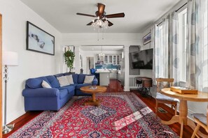 Un salon avec un canapé bleu, une table basse ronde et un tapis à motifs.