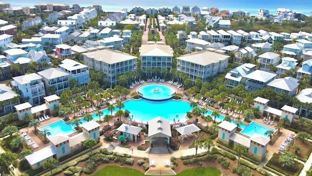 Ett hotellkomplex med flera byggnader, en central pool och utsikt över havet.