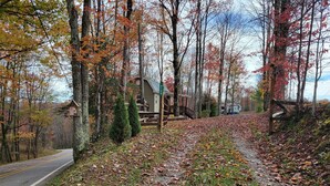 Een chalet met een grindpad, omgeven door bomen met herfstkleuren.