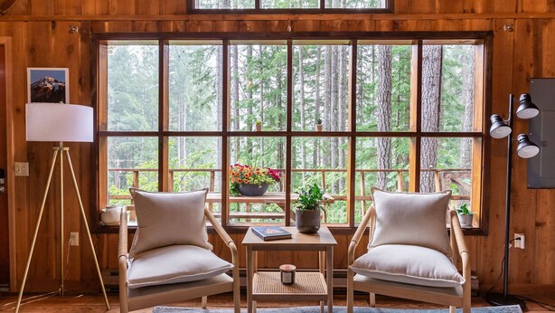 A cozy room with two chairs, a small table, and a large window offering a forest view. - Charming A-Frame @ Mt. Rainier~Nature~Relax! Pet Friendly! (Packwood)