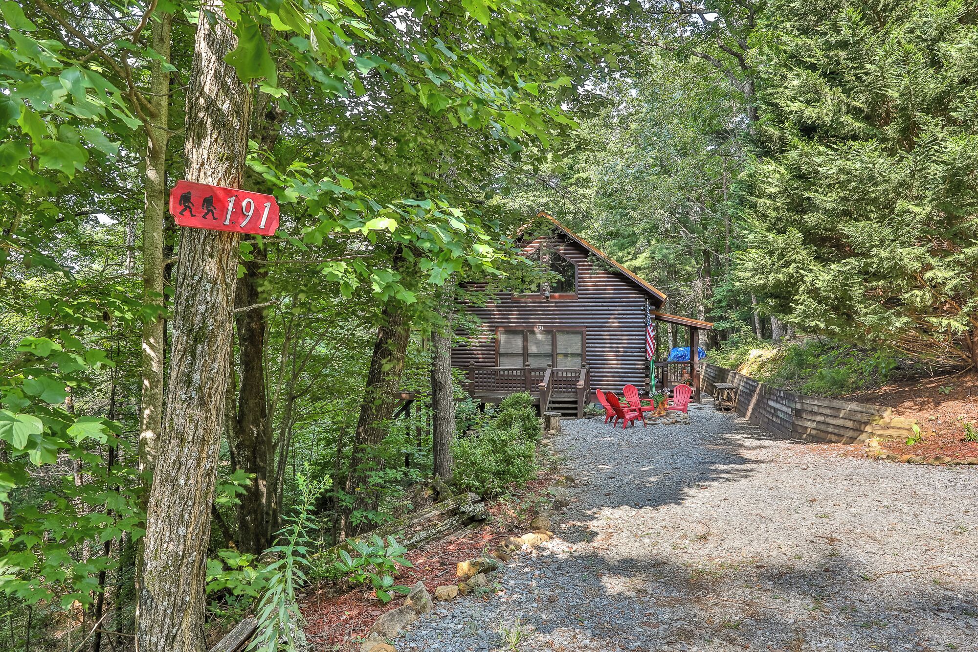 A rustic cabin with a gravel path leading to it, surrounded by dense forest.