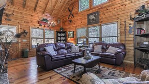 A log cabin interior with a sectional sofa, a coffee table, and a fireplace.