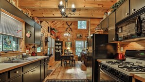 A wooden cabin interior with a kitchen, dining area, and a fireplace.