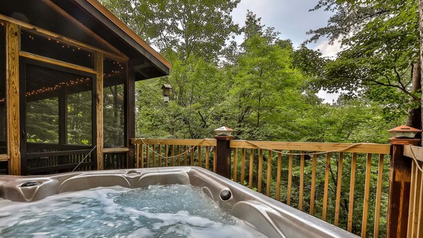 A hot tub on a wooden deck with a view of a forest.
