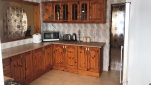 A kitchen with wooden cabinets, a microwave, a toaster, and a refrigerator.
