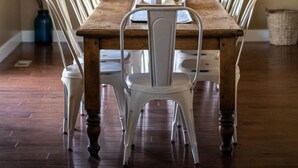 A dining area with a long wooden table, white chairs, and a brick fireplace in the background. - Highland Hideaway, Room for everyone, central to everything (Highland)
