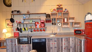 Una cocina compacta con armarios de madera, lavavajillas integrado y diferentes utensilios y electrodomésticos.