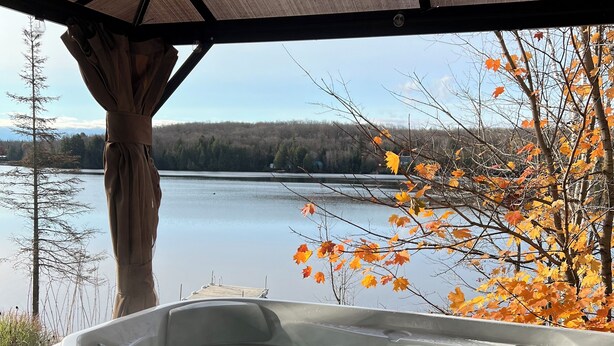 A hot tub with a view of a lake and autumn foliage. - Modern 4BR Lakefront Cottage w/ Hot Tub & Dock (Emsdale)