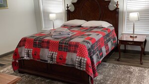 A bedroom with a wooden bed, a ceiling fan, two bedside lamps, and a patterned rug.