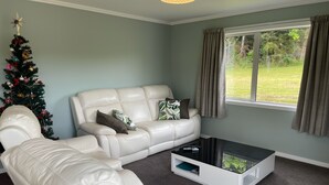 Ein Wohnzimmer mit einem weißen Ledersofa, einem Glastisch und einem Weihnachtsbaum.