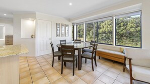 A dining area with a round table, six chairs, and a bench. - Flynn's Beach Escape ! (Port Macquarie)