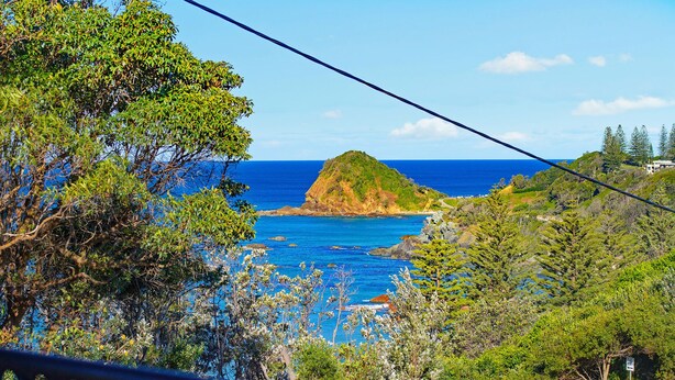 A coastal landscape with a prominent hill, clear blue sea, and lush greenery. - Flynn's Beach Escape ! (Port Macquarie)