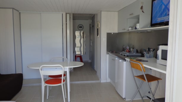 Et lille tekøkken med mikroovn, vask og spiseplads med et bord og stole.
