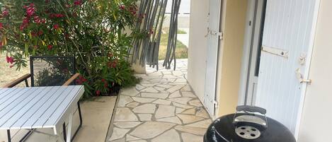 A patio with a grill, a table, and a chair.