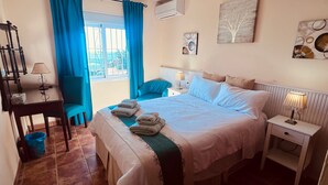 Ein Hotelzimmer mit einem Bett, einem Sessel, einem Schreibtisch und einem Fenster mit Vorhängen.