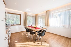Une cuisine moderne avec une table en bois, des chaises noires et un set de table rouge.