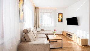 Un salon moderne avec un canapé d’angle, une table basse, un téléviseur à écran plat et un meuble en bois.