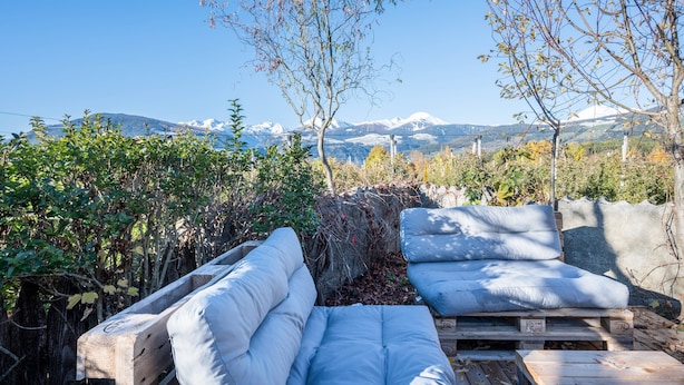 Une terrasse avec deux canapés blancs dotés de coussins, une table en bois et une vue sur des montagnes enneigées.