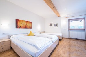 Une chambre avec deux lits, un plafond en bois, une fenêtre donnant sur un beau paysage et un tableau accroché au mur.