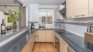 A modern kitchen with a central island, built-in cabinets, and a view of the city through the window. - Apartment "Villa Mar del Plata" with Shared Pool, Wi-Fi, Garden & Terrace (Fuengirola)