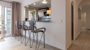 A modern kitchen with a dining area, featuring a bar counter, chairs, and a view through a glass door. - Apartment "Villa Mar del Plata" with Shared Pool, Wi-Fi, Garden & Terrace (Fuengirola)