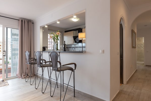 Una cocina moderna con comedor, que incluye una barra, sillas y vistas a través de un ventanal.
