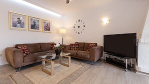 A living room with a sofa, coffee table, TV, and wall clock. - Apartment "Villa Mar del Plata" with Shared Pool, Wi-Fi, Garden & Terrace (Fuengirola)