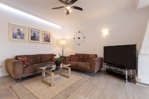 Una sala de estar con sofá, mesa de centro, televisor y un reloj de pared.