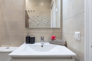 Un baño con lavamanos blanco, espejo, toalla y cortina de ducha.