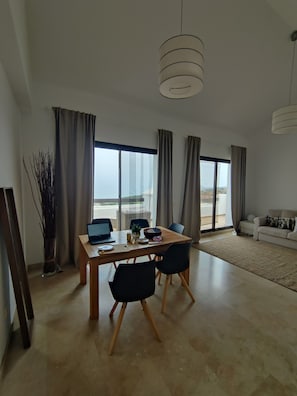 A modern living room with a dining area, large windows, and a view of the outdoors.