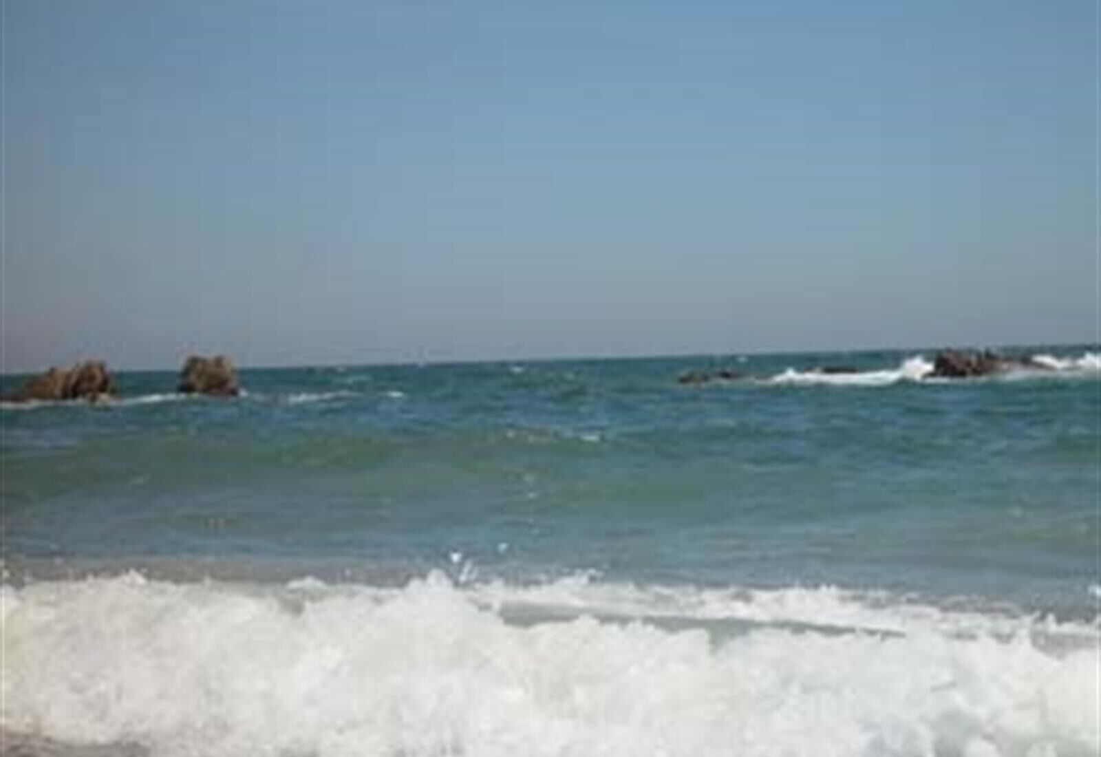 Una playa con olas y rocas en el agua.