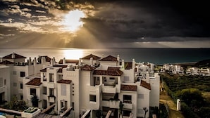 Una zona residencial costera con edificios blancos, algunos con tejados de tejas rojas, y vista al mar.