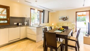 A modern kitchen with a dining area, large windows, and a view of the outdoors.
