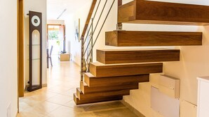 A modern staircase with wooden steps and metal railings, leading to a well-lit interior space.