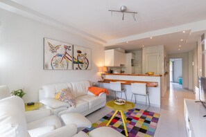 Un salon moderne avec un canapé, des fauteuils, une table basse et des œuvres d’art accrochées au mur.