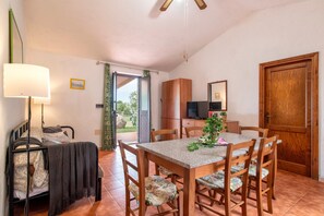 Una stanza con un letto, un tavolo con sedie, una TV e una porta in legno.